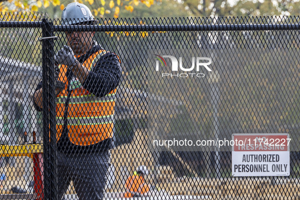 Workers erect security fences surrounding the construction site for the 2025 Presidential Inaugural Parade Reviewing Stand in Lafayette Squa...