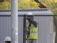 Workers erect security fences surrounding the construction site for the 2025 Presidential Inaugural Parade Reviewing Stand in Lafayette Squa...