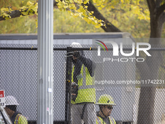 Workers erect security fences surrounding the construction site for the 2025 Presidential Inaugural Parade Reviewing Stand in Lafayette Squa...