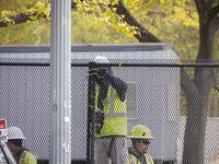 Workers erect security fences surrounding the construction site for the 2025 Presidential Inaugural Parade Reviewing Stand in Lafayette Squa...