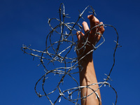 A person holds barbed wire while attending a demonstration against the Polish government's plans to suspend the right to asylum for refugees...