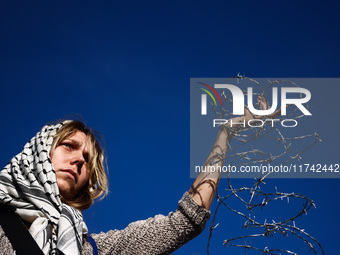 A woman holds barbed wire while attending a demonstration against the Polish government's plans to suspend the right to asylum for refugees...