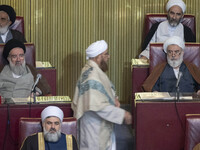 Two Shi'ite Iranian clerics look at a Sunni cleric arriving at the old Iranian Parliament building to take part in Iran's Assembly of Expert...