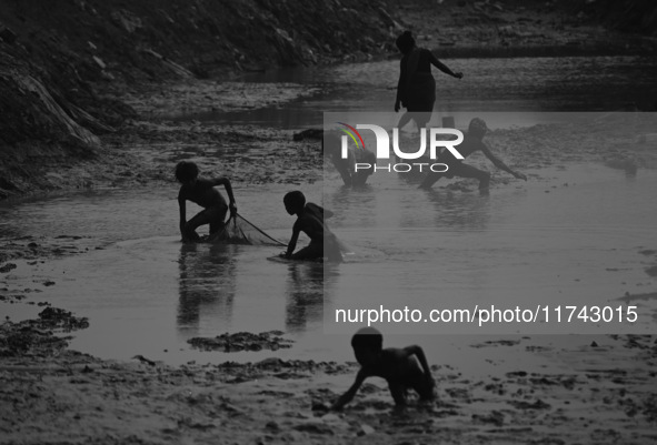 Boys catch fish in the polluted water on the banks of the river Ganges in Prayagraj, India, on November 5, 2024. 