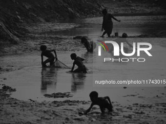 Boys catch fish in the polluted water on the banks of the river Ganges in Prayagraj, India, on November 5, 2024. (