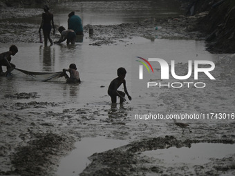 Boys catch fish in the polluted water on the banks of the river Ganges in Prayagraj, India, on November 5, 2024. (