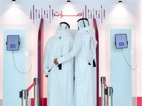 An official assists a Qatari voter in casting their electronic vote at a polling station in a general referendum on constitutional amendment...