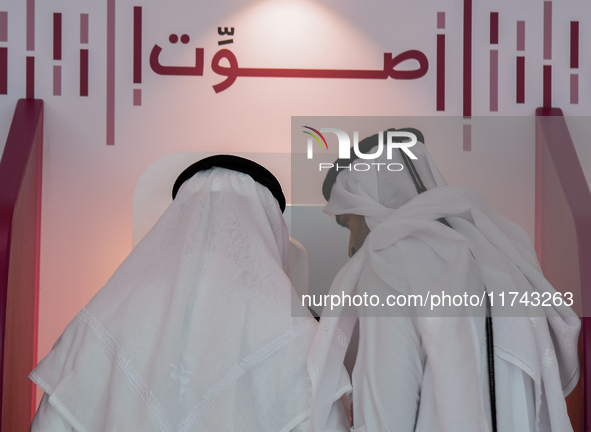 An official assists a Qatari voter in casting their electronic vote at a polling station in a general referendum on constitutional amendment...