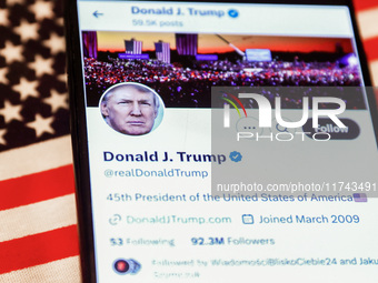 Donald J. Trump social media site on X, formerly known as Twitter, is displayed on a mobile phone screen with US flag in the background for...