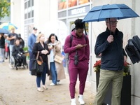 A group of people waits outside 125 S Jefferson St, Chicago, IL, to vote in the 2024 Presidential election. It is raining, so some of them h...