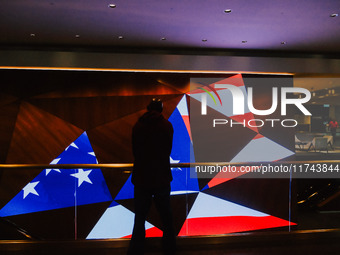 A man stands in front of a display screen showing the American flag on Election Day 2024 in Minneapolis, Minnesota, on November 5, 2024. (