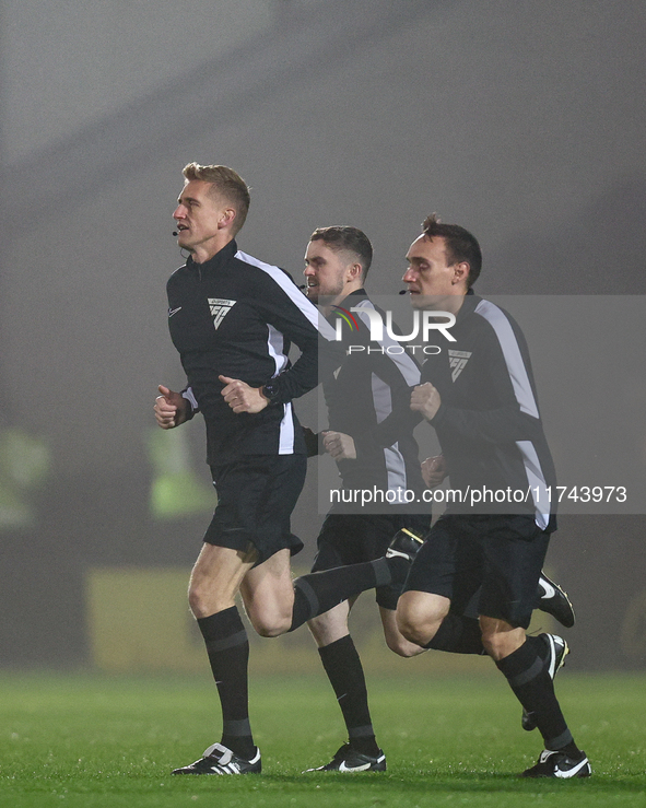 Referee Scott Oldham leads his assistants as they warm up during the Sky Bet League 1 match between Burton Albion and Crawley Town at the Pi...