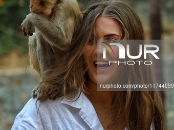 A tourist poses with a macaque at the Shrine Galta Ji Temple in Jaipur, Rajasthan, India, on November 5, 2024. (