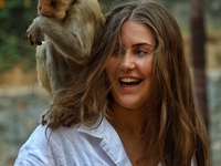 A tourist poses with a macaque at the Shrine Galta Ji Temple in Jaipur, Rajasthan, India, on November 5, 2024. (