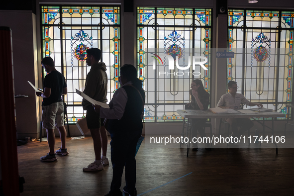 Voters wait to cast their ballots for President, Congress,and local races for the 2024 election in a room of stained glass windows at the Mu...