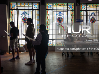 Voters wait to cast their ballots for President, Congress,and local races for the 2024 election in a room of stained glass windows at the Mu...