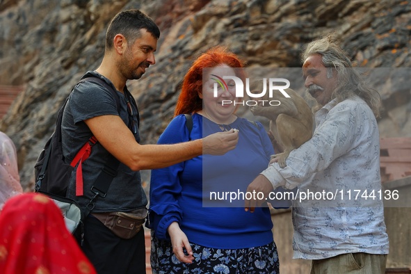 A tourist poses with a macaque at the Shrine Galta Ji Temple in Jaipur, Rajasthan, India, on November 5, 2024. 