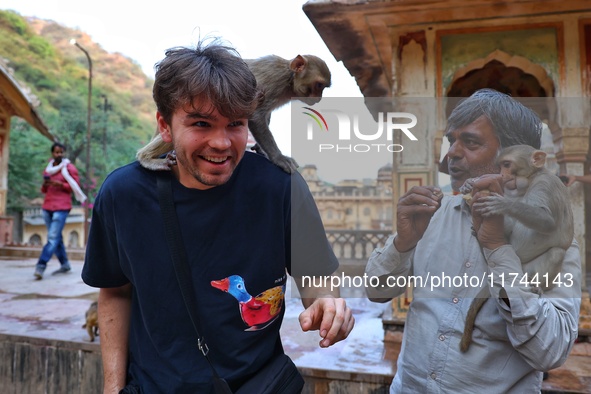 A tourist poses with a macaque at the Shrine Galta Ji Temple in Jaipur, Rajasthan, India, on November 5, 2024. 