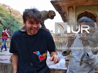 A tourist poses with a macaque at the Shrine Galta Ji Temple in Jaipur, Rajasthan, India, on November 5, 2024. (