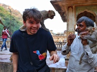 A tourist poses with a macaque at the Shrine Galta Ji Temple in Jaipur, Rajasthan, India, on November 5, 2024. (