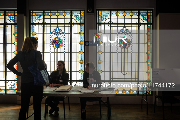 A voter picks up her ballot to vote for President, Congress, and local races for the 2024 election in a room with stained glass windows at t...