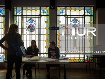 A voter picks up her ballot to vote for President, Congress, and local races for the 2024 election in a room with stained glass windows at t...