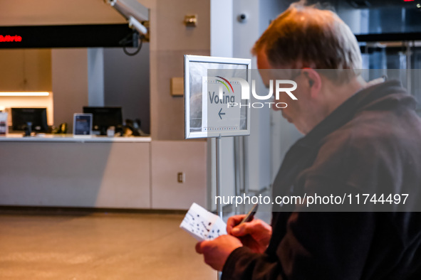 An election official sits inside the Guthrie Theatre with a sign pointing to the polling location on Election Day 2024 in Minneapolis, Minne...