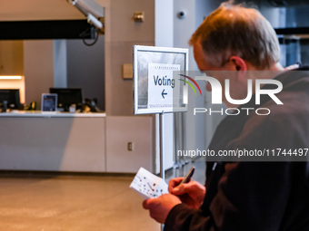 An election official sits inside the Guthrie Theatre with a sign pointing to the polling location on Election Day 2024 in Minneapolis, Minne...