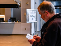 An election official sits inside the Guthrie Theatre with a sign pointing to the polling location on Election Day 2024 in Minneapolis, Minne...