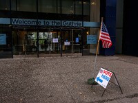 A sign and flag indicating a polling place for voters are seen next to the Guthrie Theatre on Election Day 2024 in Minneapolis, Minnesota, o...