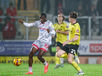 Number 22, Ade Adeyemo of Crawley Town, is in attacking action as number 21, Alex Bannon of Burton Albion, challenges during the Sky Bet Lea...