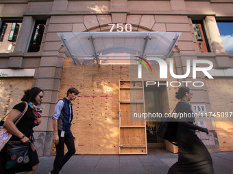 People walk past businesses near the White House that are boarded up in the event of violence following today's election for president in Wa...