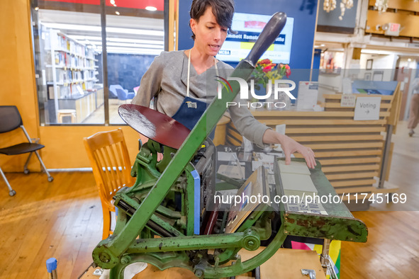 Elysa Voshell, Executive Director of the Minnesota Center for Book Arts, prints postcards using a traditional letterpress for voters to grab...