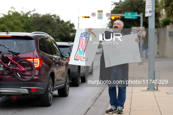 A supporter of Democratic candidate for U.S. Senate Collin Allred holds signs against incumbent Ted Cruz (R-TX) outside the polling place at...