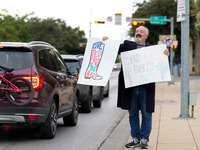 A supporter of Democratic candidate for U.S. Senate Collin Allred holds signs against incumbent Ted Cruz (R-TX) outside the polling place at...