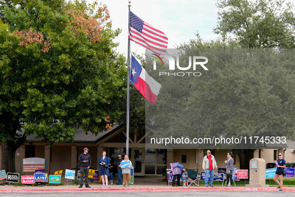 Campaign workers greet voters outside a polling place in suburban Austin, Texas, on November 5, 2024, as poll-goers meet short lines at most...