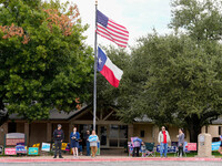 Campaign workers greet voters outside a polling place in suburban Austin, Texas, on November 5, 2024, as poll-goers meet short lines at most...