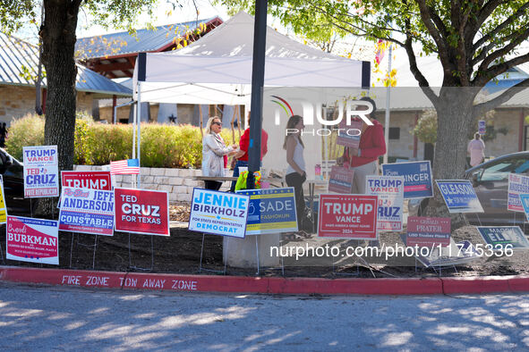 Campaign workers greet voters outside a polling place in suburban Austin, Texas, on November 5, 2024, as poll-goers meet short lines at most...