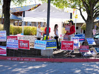 Campaign workers greet voters outside a polling place in suburban Austin, Texas, on November 5, 2024, as poll-goers meet short lines at most...