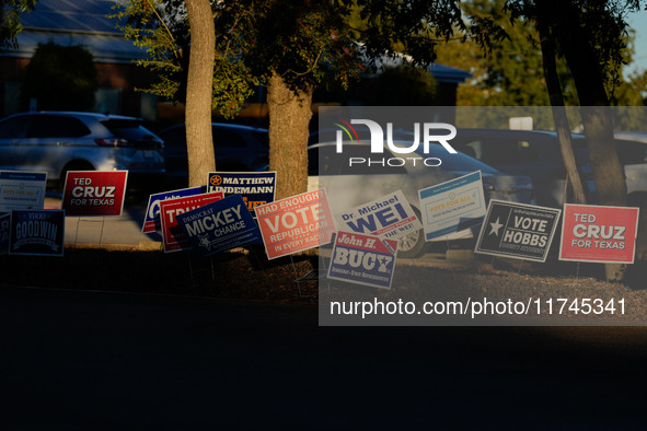 Campaign signs are in the foreground as cars line up to enter a parking lot outside a polling place in suburban Austin, Texas, on November 5...