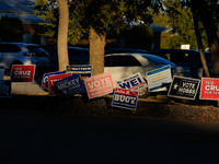 Campaign signs are in the foreground as cars line up to enter a parking lot outside a polling place in suburban Austin, Texas, on November 5...