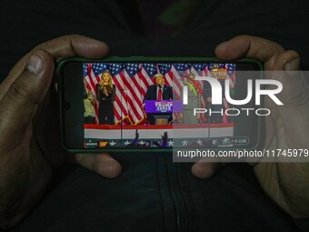 A man watches a live telecast of a speech by former US President and Republican presidential candidate Donald Trump on his mobile phone in S...