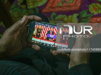 A man watches a live telecast of a speech by former US President and Republican presidential candidate Donald Trump on his mobile phone in S...