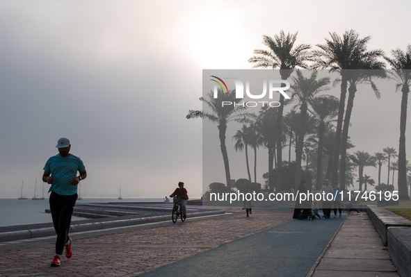 People walk along the Doha Corniche in heavy fog in Doha, Qatar, on November 6, 2024. 