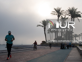 People walk along the Doha Corniche in heavy fog in Doha, Qatar, on November 6, 2024. (