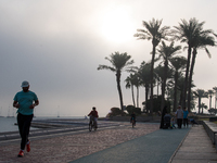 People walk along the Doha Corniche in heavy fog in Doha, Qatar, on November 6, 2024. (