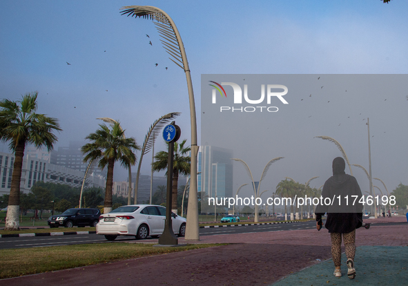 People walk along the Doha Corniche in heavy fog in Doha, Qatar, on November 6, 2024. 