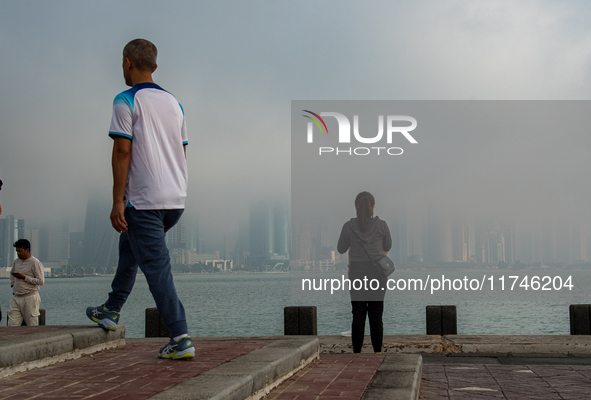 People walk along the Doha Corniche in heavy fog in Doha, Qatar, on November 6, 2024. 