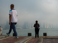 People walk along the Doha Corniche in heavy fog in Doha, Qatar, on November 6, 2024. (