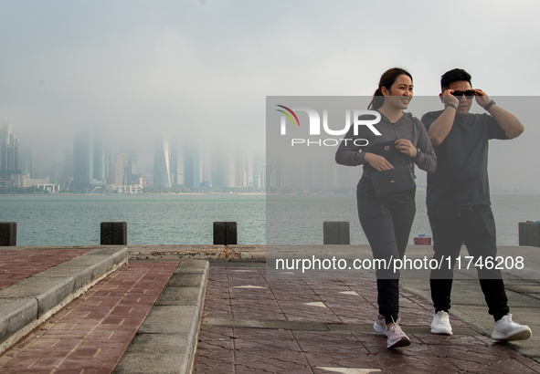 People walk along the Doha Corniche in heavy fog in Doha, Qatar, on November 6, 2024. 